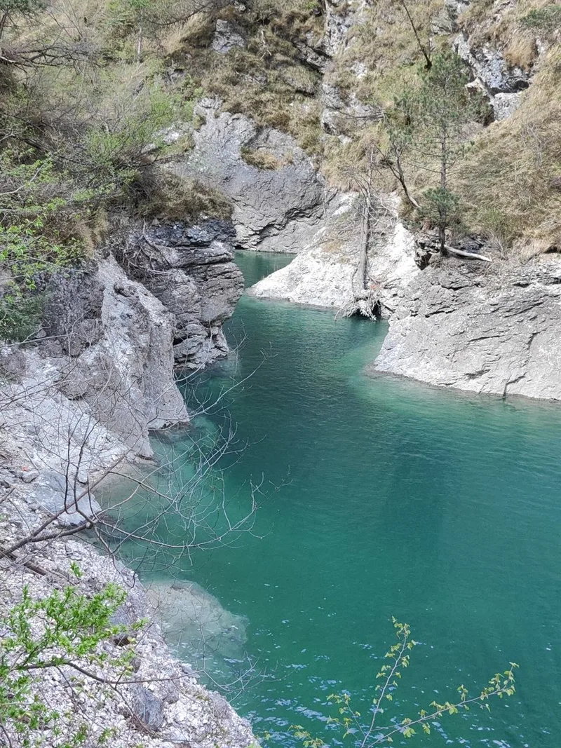 Piscina naturale profonda con acqua turchese nella Val Falcina, pareti rocciose verticali